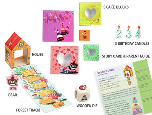 Collection of children's play items including a house, cake blocks, candles, and a story card on a white background.