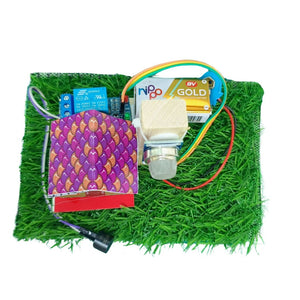 Go_Science_Classroom_Series_Gas_Alert_Alarm_MQ135_Gas_Sensor_School_Project_Demonstration_Kit_image 3. An electronics kit featuring a purple and gold patterned circuit board, a white push-button switch, a blue Nipo Gold battery, and various wires, all arranged on a green artificial grass mat against a white background.