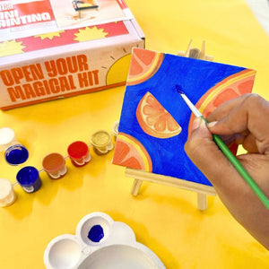 Kitsters DIY Mini Painting Kit with canvas on easel featuring citrus fruit design, paint pots, and brush on yellow background.
