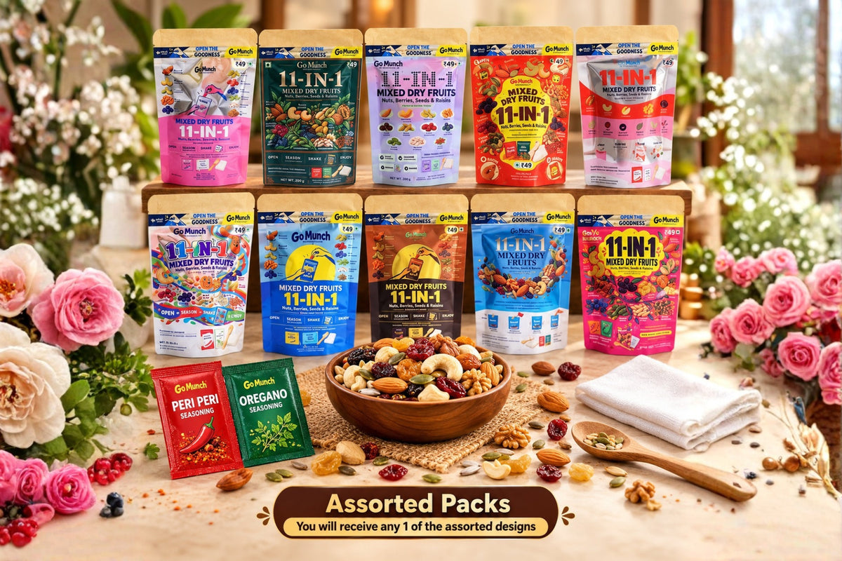 A promotional display of multiple Gf1000 11-In-1 mixed dry fruit pouches arranged on a wooden stand, with a bowl of mixed nuts and dried fruits in front, surrounded by pink roses and a folded white cloth on a table.