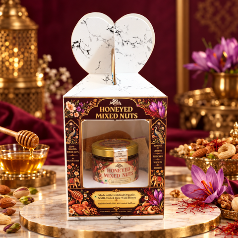 Go Munch by Go Science Honey mixed nuts made with organic honey and saffron retail and gift  pack. A boxed jar of Honeyed Mixed Nuts displayed on a marble pedestal with decorative nuts, a honey dipper, and purple flowers around it. The packaging features a white heart-shaped lid and ornate floral and gold detailing, with the jar visible through a front window.