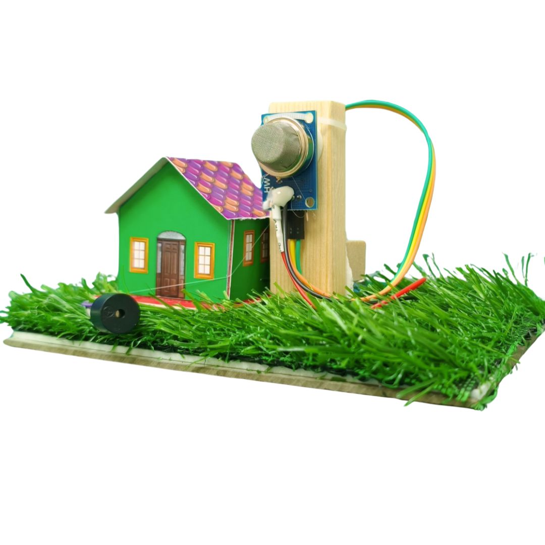 Go Science Classroom Series Gas Alert Alarm (MQ135 Gas Sensor) School Project & Demonstration Kit image 1. A small toy or model setup featuring a green house with a purple patterned roof, mounted on artificial grass beside a wooden post with a MQ135 gas sensor and multicolored wires, isolated on a white background.