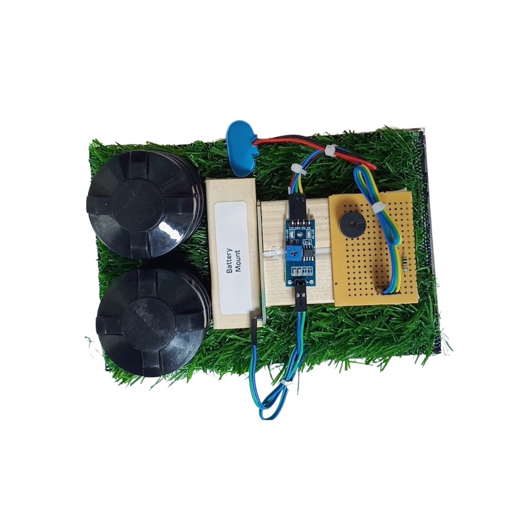 Go Science Classroom Series Smart Soil Moisture Detection kit for School Project & Demonstration kit model image 3. A small electronic DIY project kit on a white background, featuring a green artificial grass base with a battery, two black wheels, a blue motor, a breadboard, and a yellow circuit board.