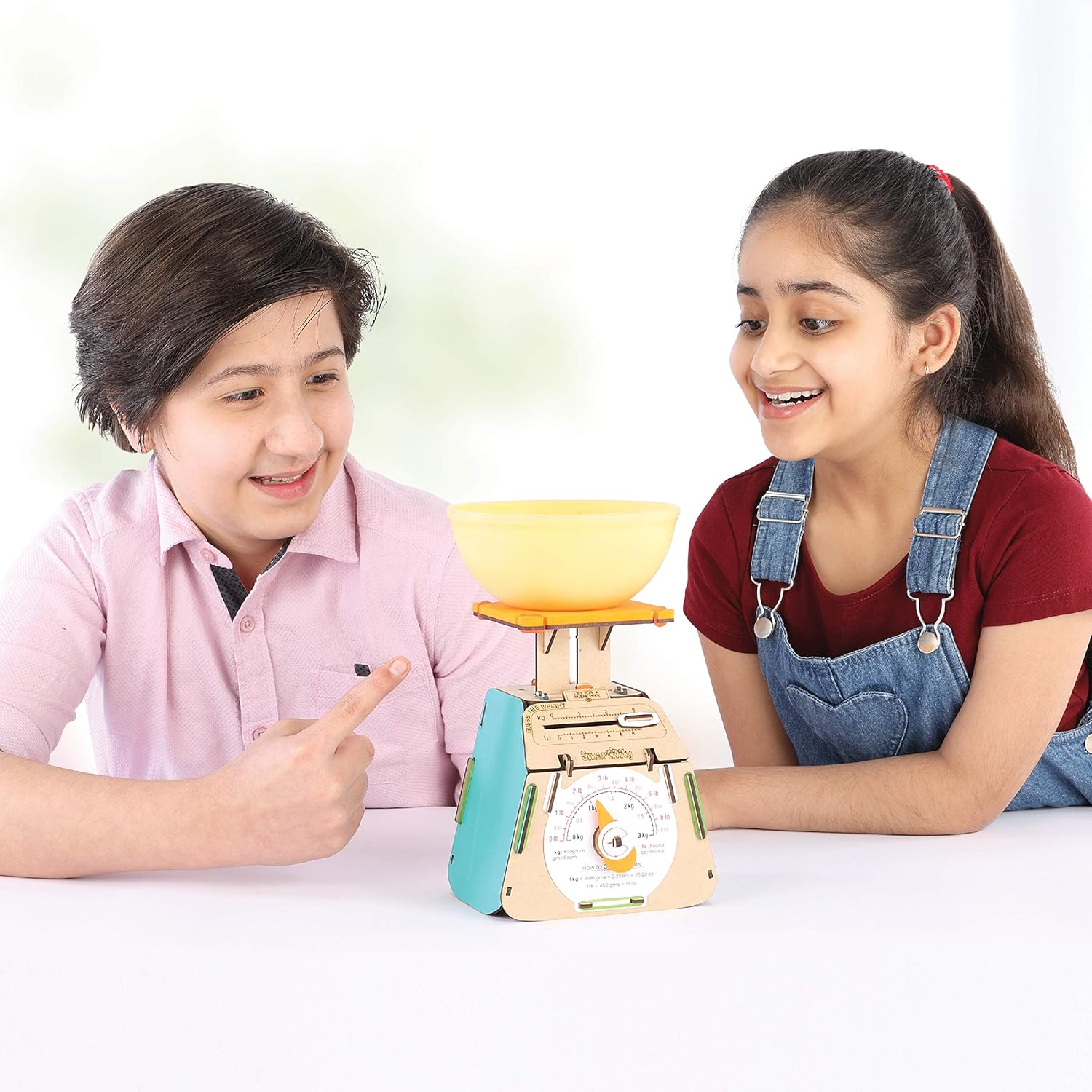 Two children interacting with a toy scale on a white background. Smartivity Weighing Machine available at Go Science Product Image 5