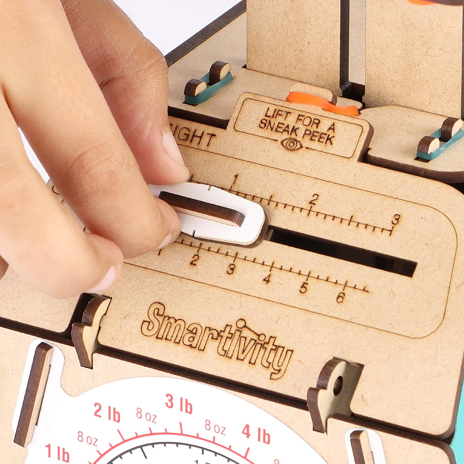 Wooden measuring tool with a hand lifting a cover, branded 'Smartivity'. Smartivity Weighing Machine available at Go Science Product Image 6