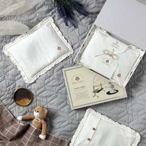 Baby accessories including pillows and a card on a textured surface with lavender flowers.