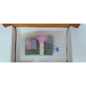 A small packaged item wrapped in bubble wrap inside an open cardboard box, photographed against a white background. Windmill Generator (Windturbine) School Project go science classroom series image 7